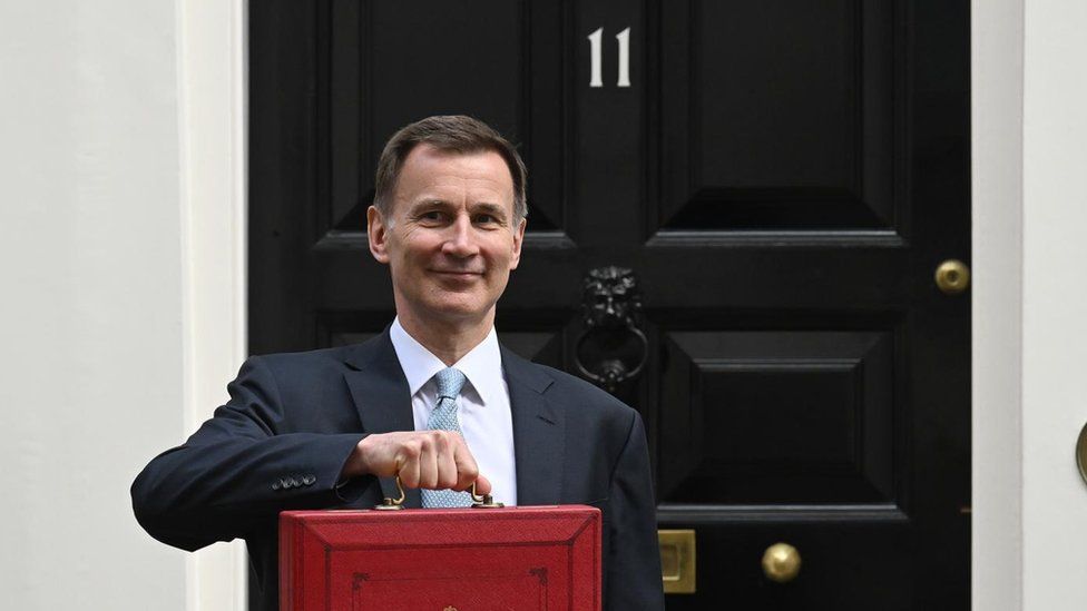 Chancellor Jeremy Hunt holds up his budget red box in front of the door of Number 11