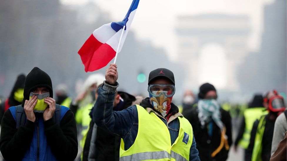 Masked protesters wearing yellow vests, a symbol of a French drivers" protest against higher fuel prices, take part in a demonstration on the Champs-Elysees in Paris, France, November 24, 2018.