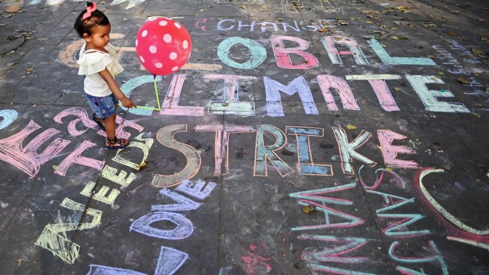 A girl walks over a chalk graffiti made by artists as part of a street art on climate change awareness at a shopping arcade in New Delhi on March 20, 2022.