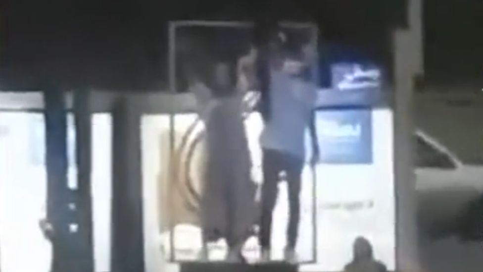 In grainy footage posted on social media, two protesters appear to climb onto a platform as part of a protest on Shariati Street, Tehran, Iran