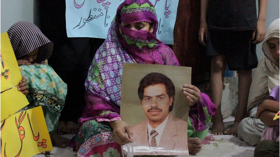 Safia Bano displays the picture of her husband Imdad Ali, a death row prisoner, while she sits with other family members in Burewala, in central Pakistan, Sunday, Sept. 18, 2016.