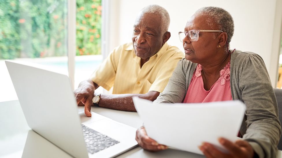Пожилая пара смотрит на счета и ноутбук