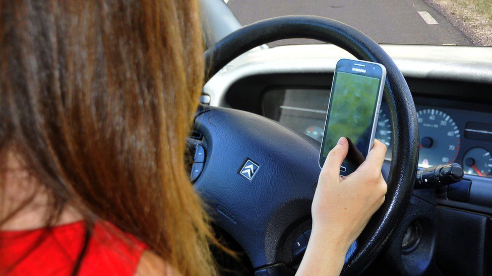 A person driving a car while holding a mobile phone