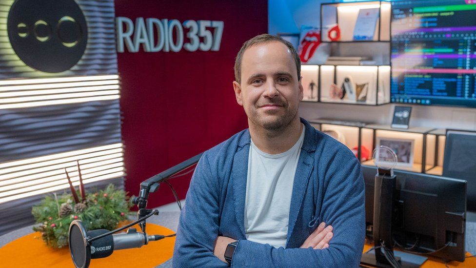 Pawel Soltys, boss of Radio 357, sits against desk inside Radio 357 sutdio