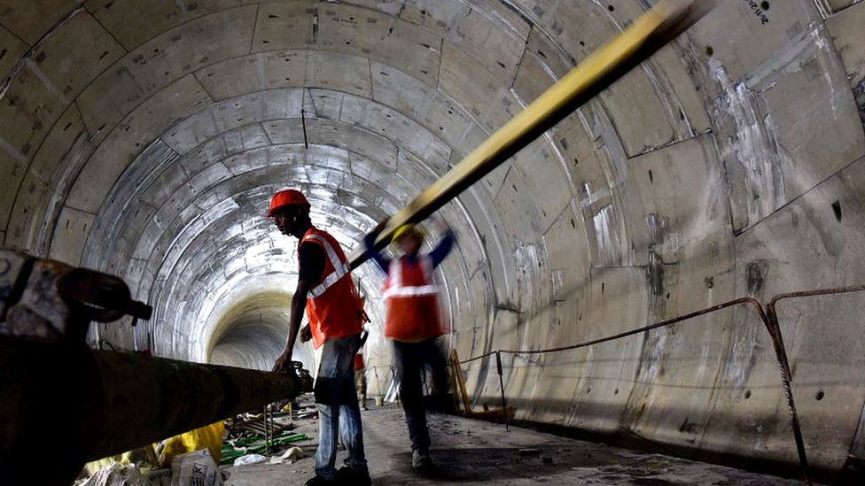 Рабочий несет балку внутри туннеля для дорожного проекта недалеко от Мумбаи