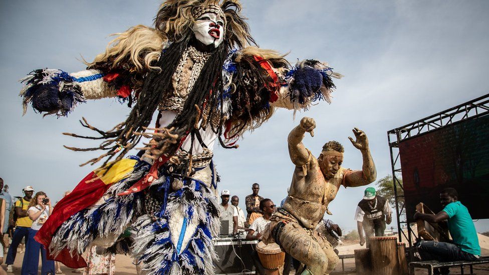 Performers dance along the coastal walkway on May 21, 2022 as part of the Dakar Biennale.
