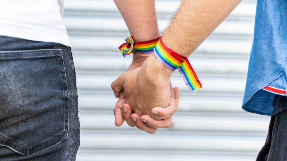 A couple holding hands with rainbow bracelets