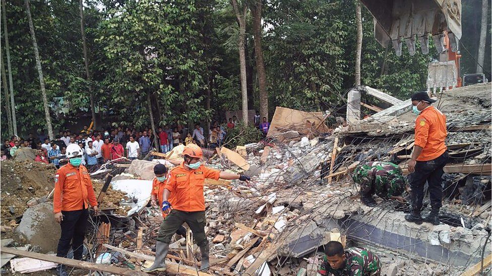 Indonesian search and rescue personnel stood next to a pile of rubble from a collapsed building in Aceh province on 7 December 2016.