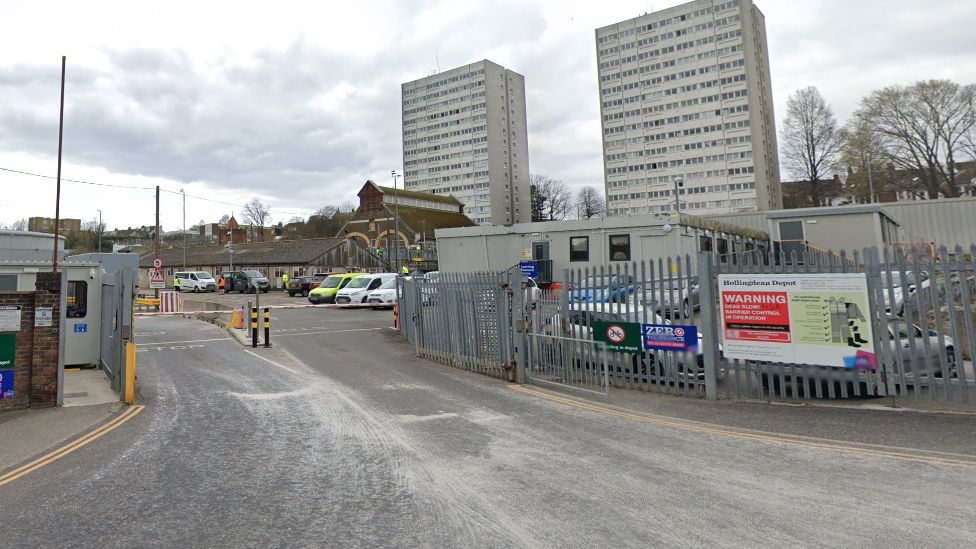 Waste depot in Hollingdean - a gate with signs and two tower blocks in the background