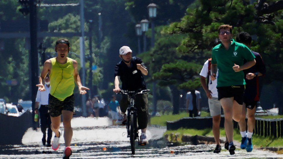People jog on a road amid heat haze in front of the Imperial Palace in Tokyo