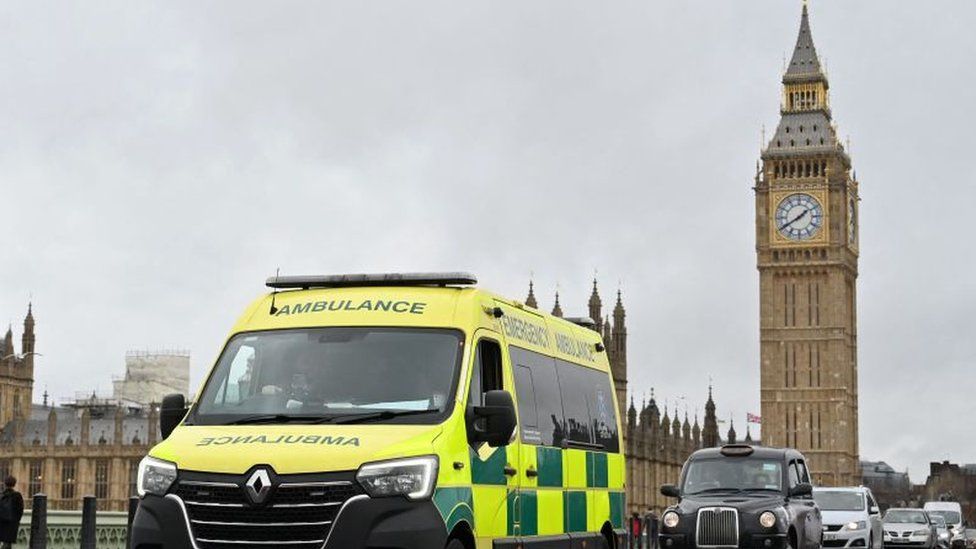 An ambulance drives over Westminster Bridge backdropped by the Elizabeth Tower