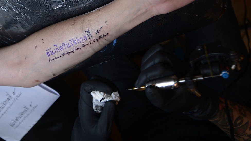 Tattoo reads in Thai and English: "I was born in the reign of King Rama IX of Thailand"