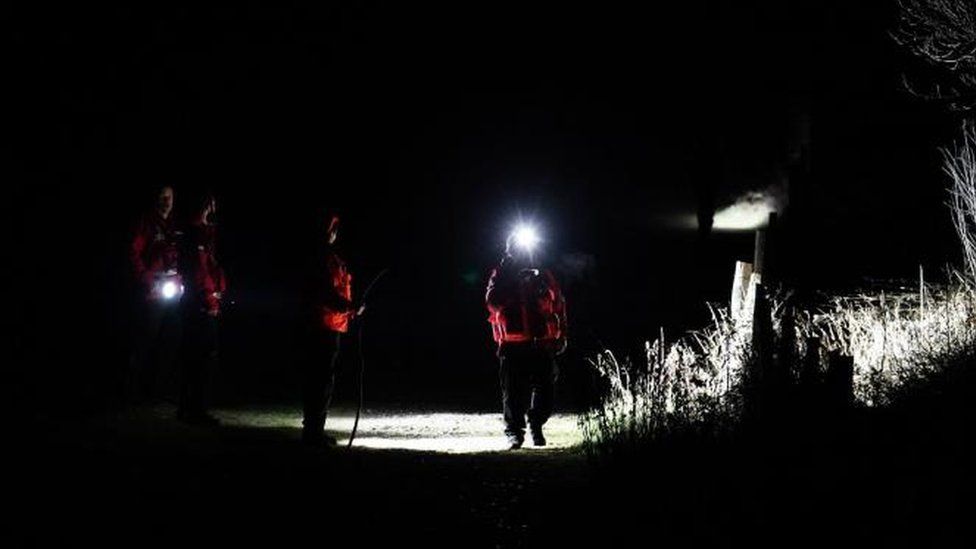 A search team with torches in a dark fields
