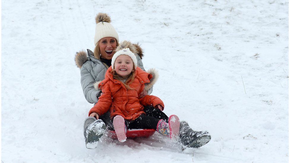 A woman and child sledging down a hill