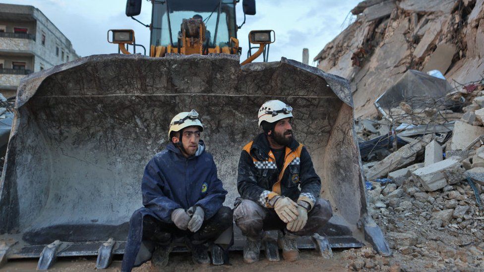 White Helmet Syrian rescue workers sit on an excavator on in the town of Sarmada in Syria
