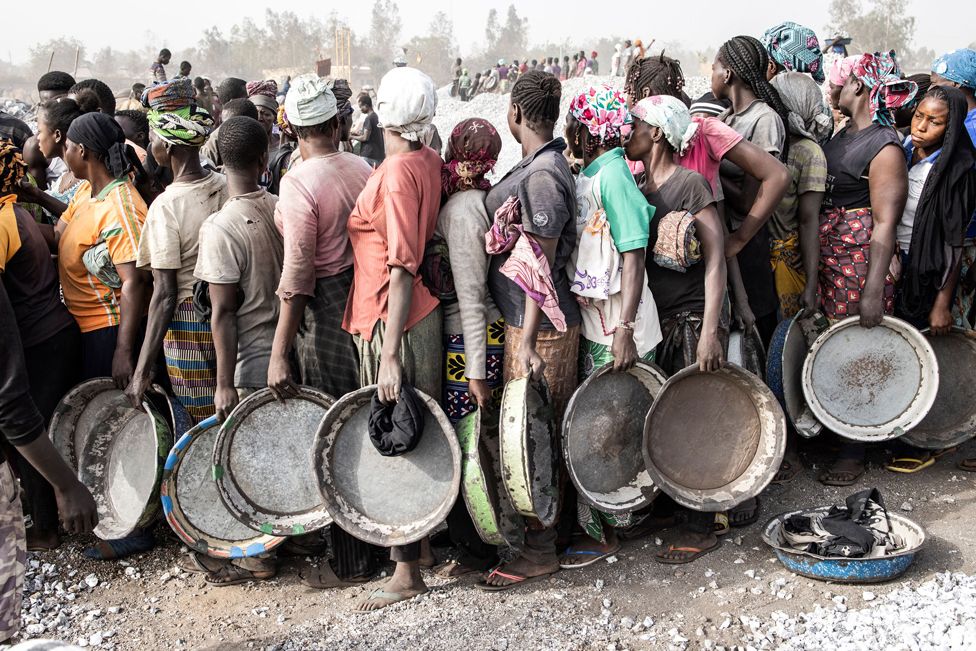 Women wait in line to collect their pay at a granite mine in Ouagadougou, Burkina Faso