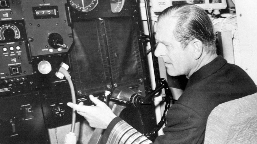 The Duke of Edinburgh, in uniform of the Admiral of the Fleet, sits at the wheel of the nuclear-powered submarine HMS Churchill