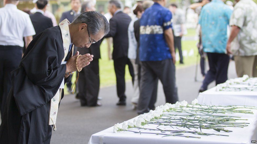 Bishop Eric Matsumoto bows and prays after presenting a flower during a service to commemorate 70 years since Pearl Harbor-Hickam, on 14 August, 2015.