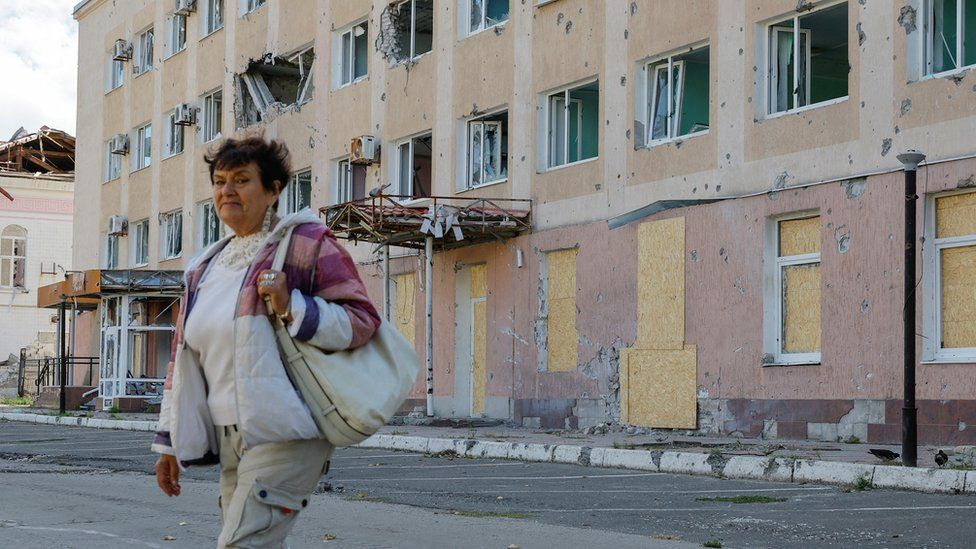 A woman walks past a shelled building in Lysychansk, a city in Ukraine's Luhansk region