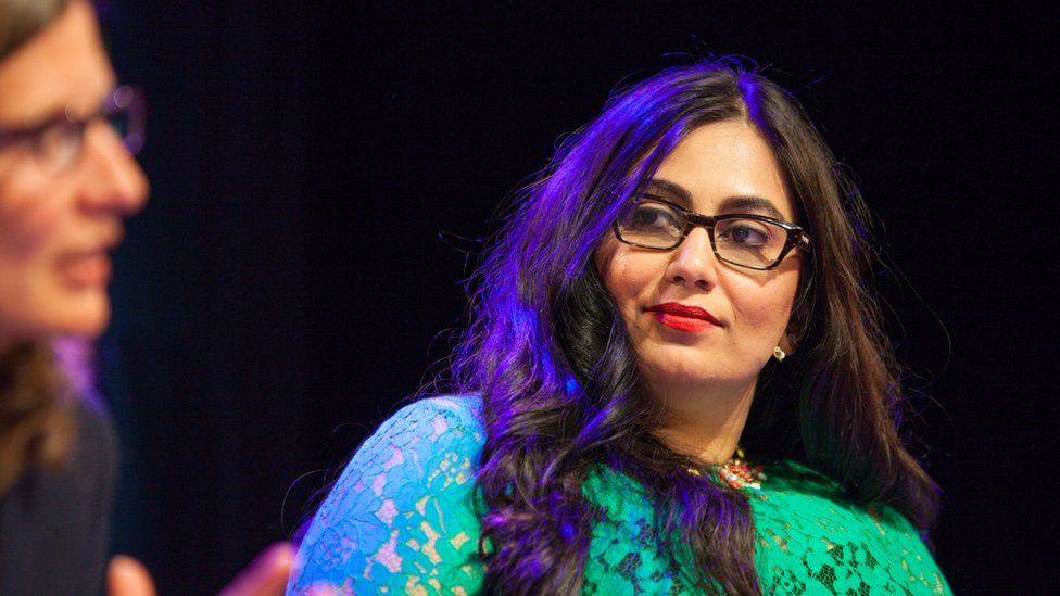 Shazia Awan-Scully, She is wearing glasses and a turquioise dress as she listens to the debate