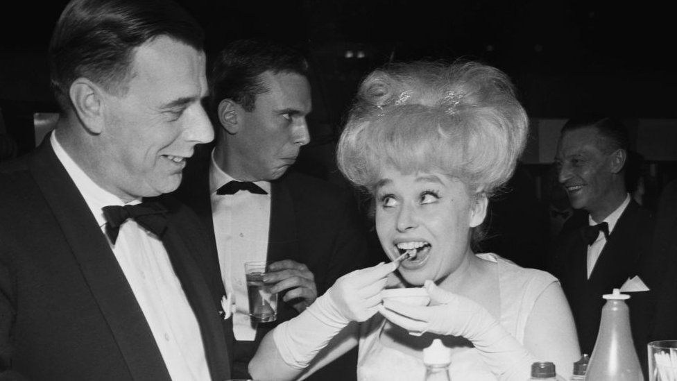 Old black and white picture of the actress Barbara Windsor eating whelks