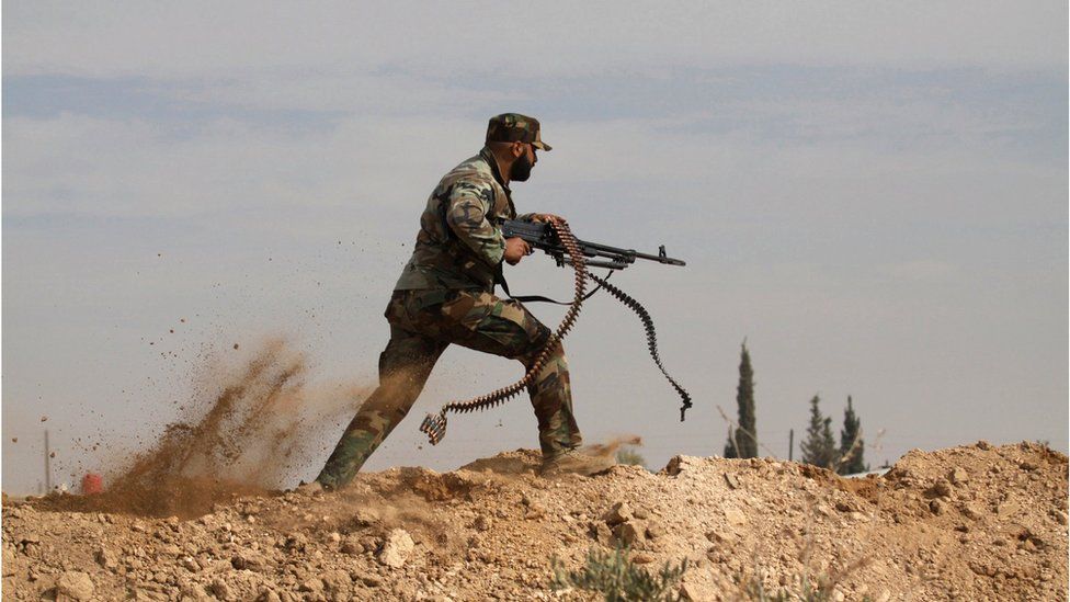 A Shiite fighter carrying a machine gun dodges bullets fired by Syrian rebels in the town of Hatita, outside Damascus, Syria. 22 November 2013.