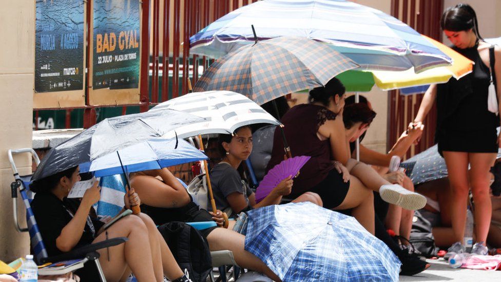 Несколько человек укрываются от жары под зонтиками в Мурсии на юго-востоке Испании