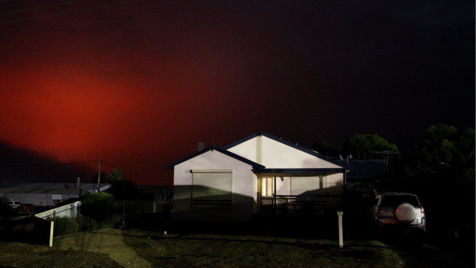 Nearby fire turns the sky dark red over a house in Kingscote on 10 January