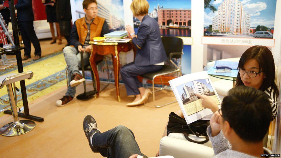 Chinese investors talks with agents for a British property investment company at an international property exhibition in Beijing on May 17, 2014