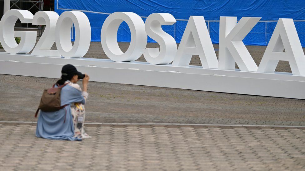 A woman takes a picture of a G20 Osaka design set up outside the venue for the G20 Osaka Summit in Osaka on June 26, 2019, ahead of the start of the summit later this week.