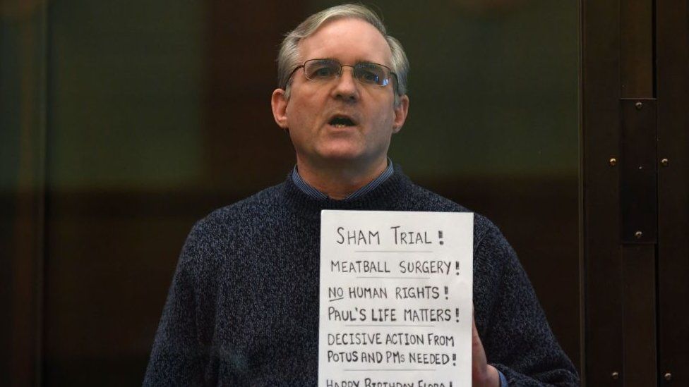 Пол Уилан, бывший морской пехотинец, держит плакат на суде