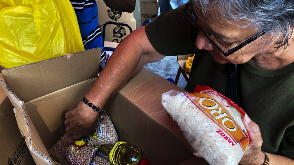 Woman inspects boxes of food from the state-run programme, Clap