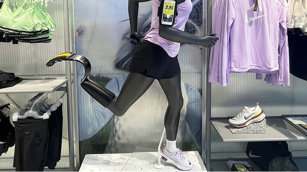 An amputee mannequin in a Nike store with one running shoe and one running blade