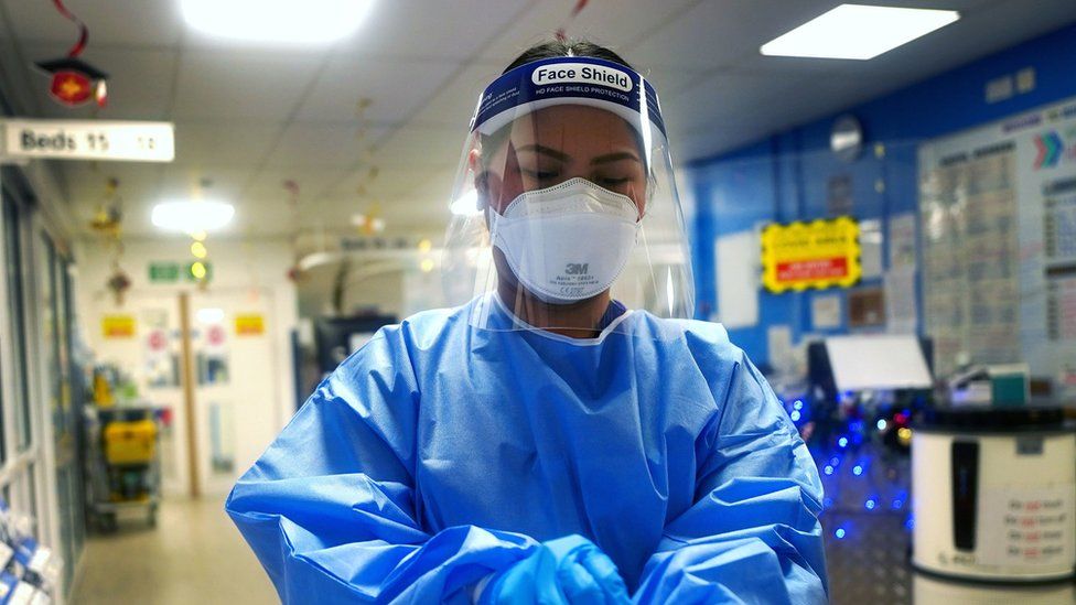 A nurse puts on gloves in a London hospital