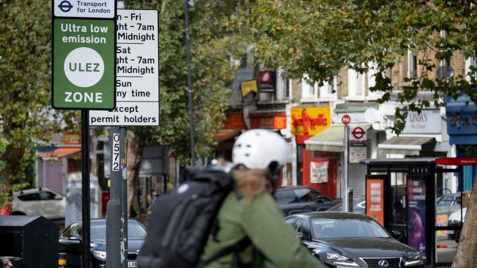 A cyclist travels past a ULEZ sign on a road in East Dulwich.