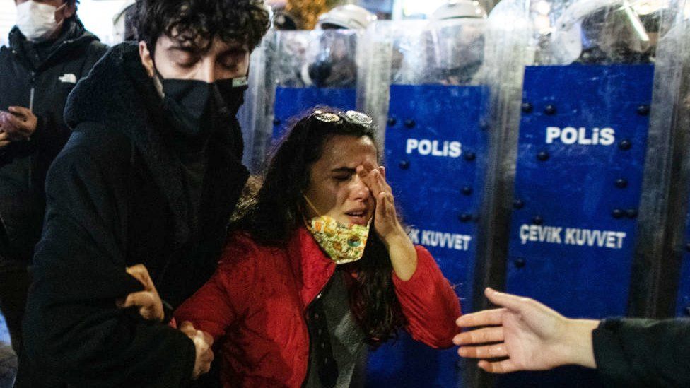 Woman rubbing her eyes infront of police