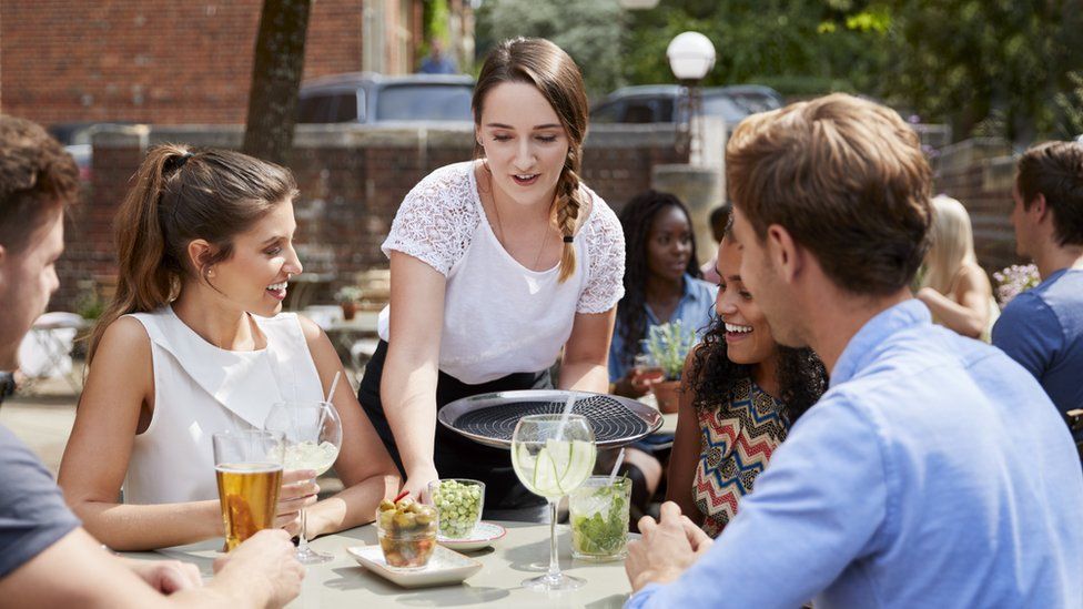 A waitress serving food in a pub garden