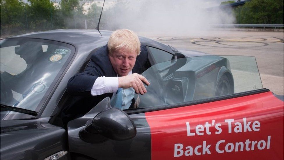 Boris Johnson, emerges from a Ginetta sport car with the logo 'Let's take back control' on the side.