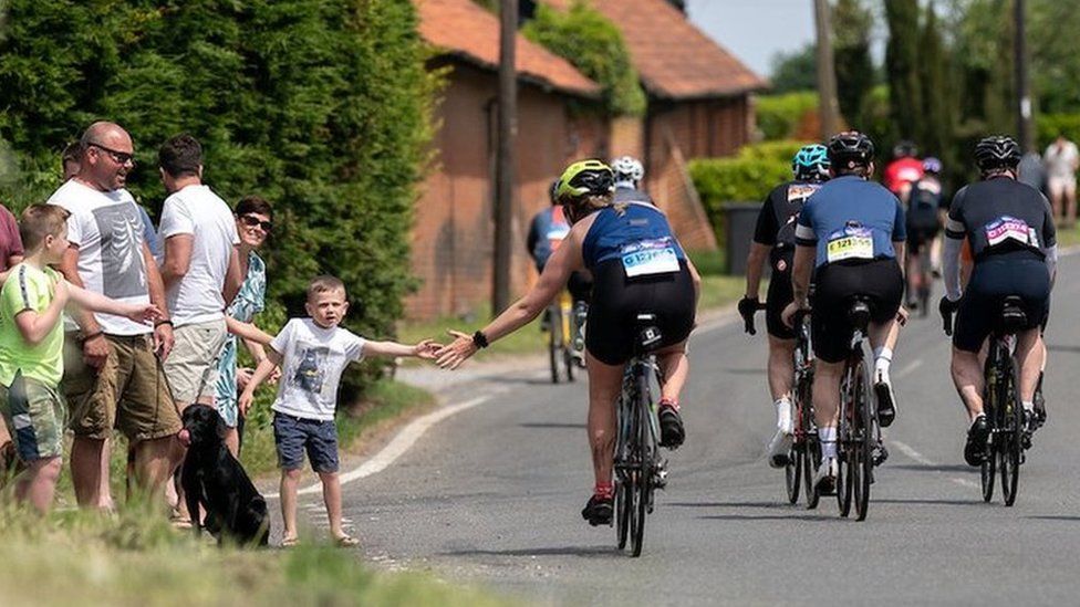 A cyclist high-fives a young boy