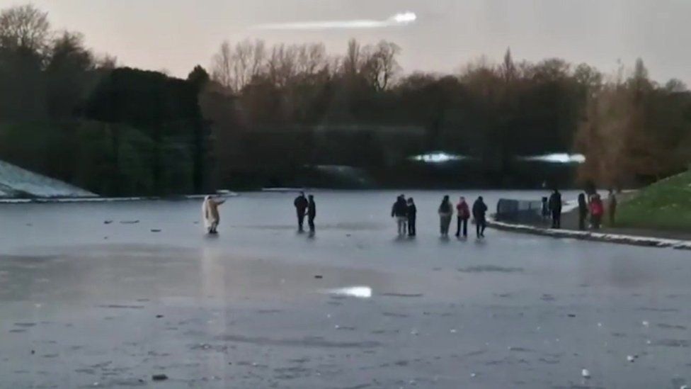People skating on icy pond