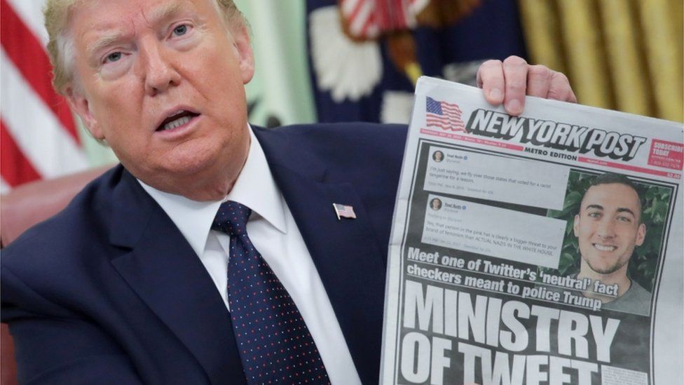 President Donald Trump holds up a front page of the New York Post as he speaks to reporters while discussing an executive order on social media companies in the Oval Office of the White House in Washington,28 May 2020