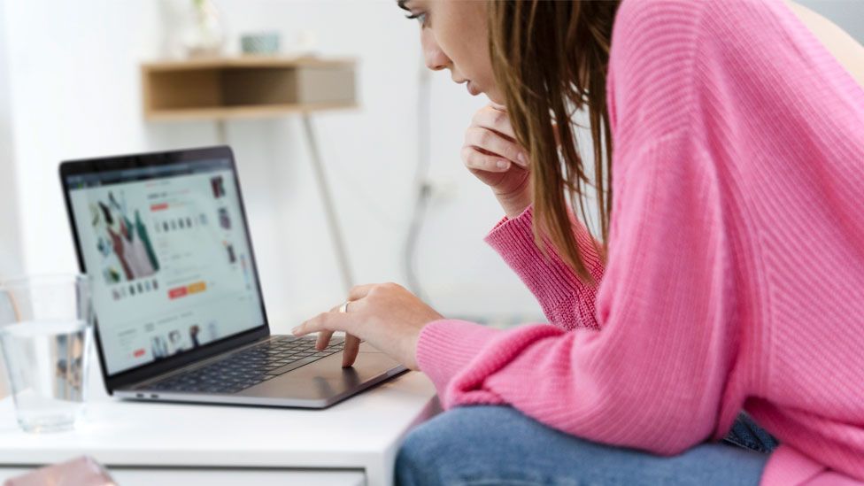 A stock image of a woman online shopping at home