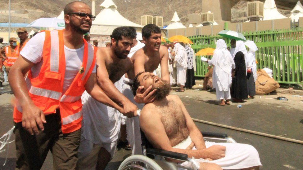Saudi emergency personnel and Hajj pilgrims push a wounded person in a wheelchair at the site where at least 450 were killed and hundreds wounded in a stampede in Mina, near the holy city of Mecca, at the annual hajj in Saudi Arabia on September 24, 2015.