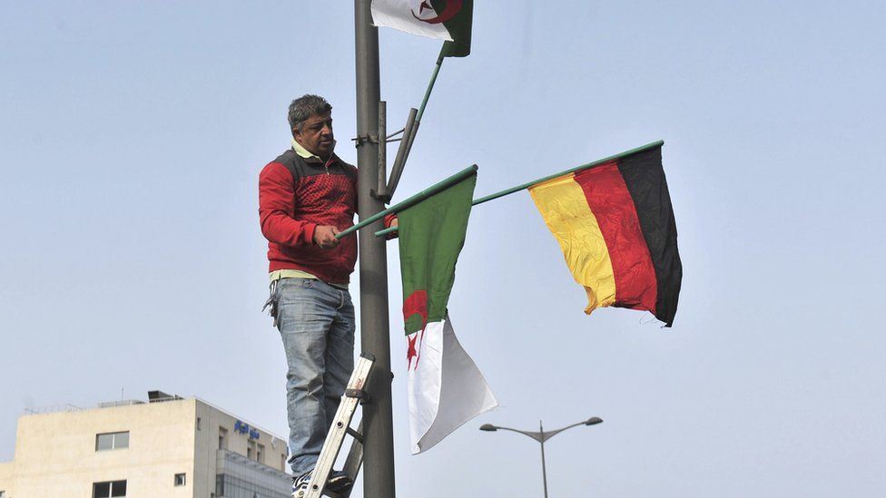 A worker in Algiers removes national and German flags in Algiers, Algeria - Monday 20 February 2017