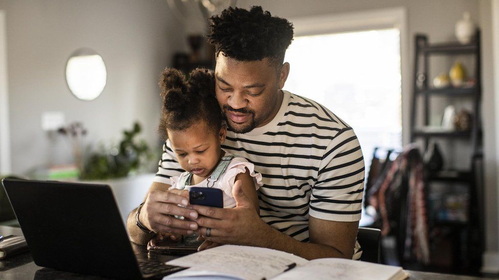 A stock photo of a child and adult browsing online