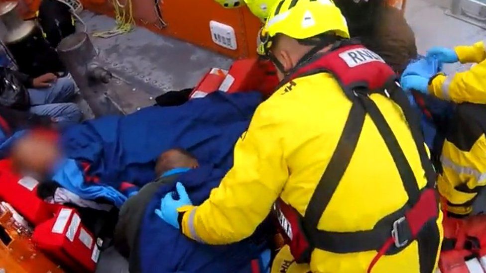 A still from the video footage shows an RNLI man attending to a person on the floor of his lifeboat