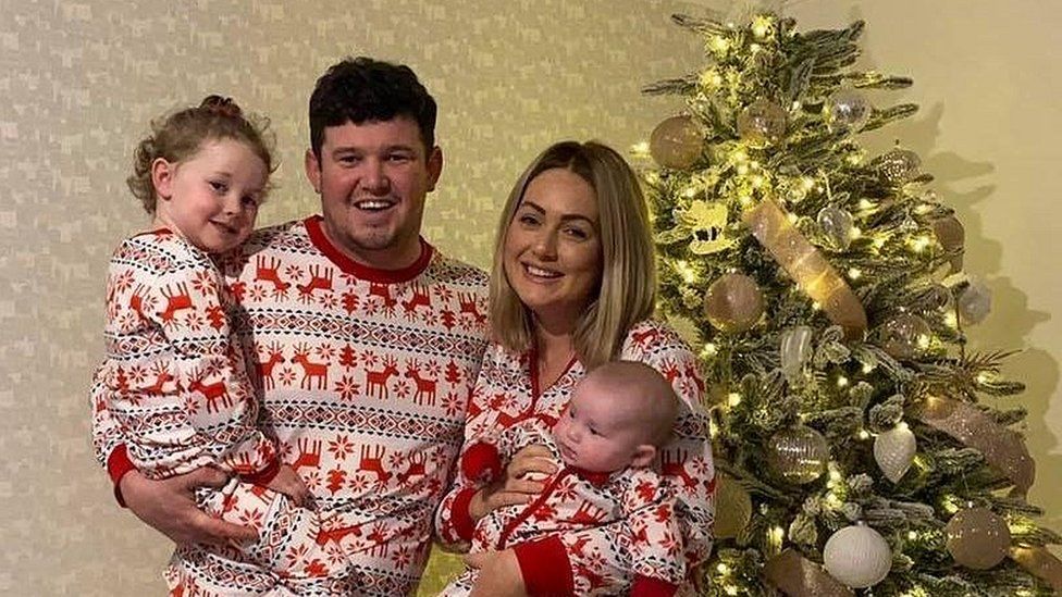 Abby Lever with her husband Ewen and their two children Ayla and Poppy stood beside a Christmas tree.