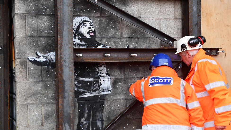 Contractors inspect the Banksy
