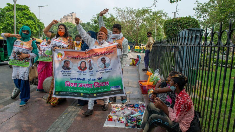 Демонстранты выкрикивают лозунги и держат знамя во время марша во Всемирный день народонаселения в Нью-Дели.