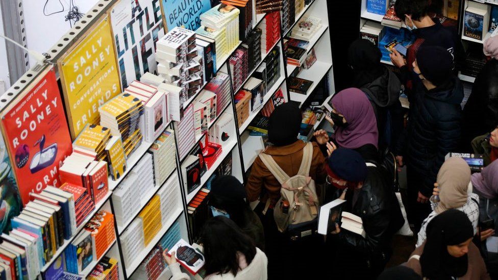 People looking at books on a book shelf.